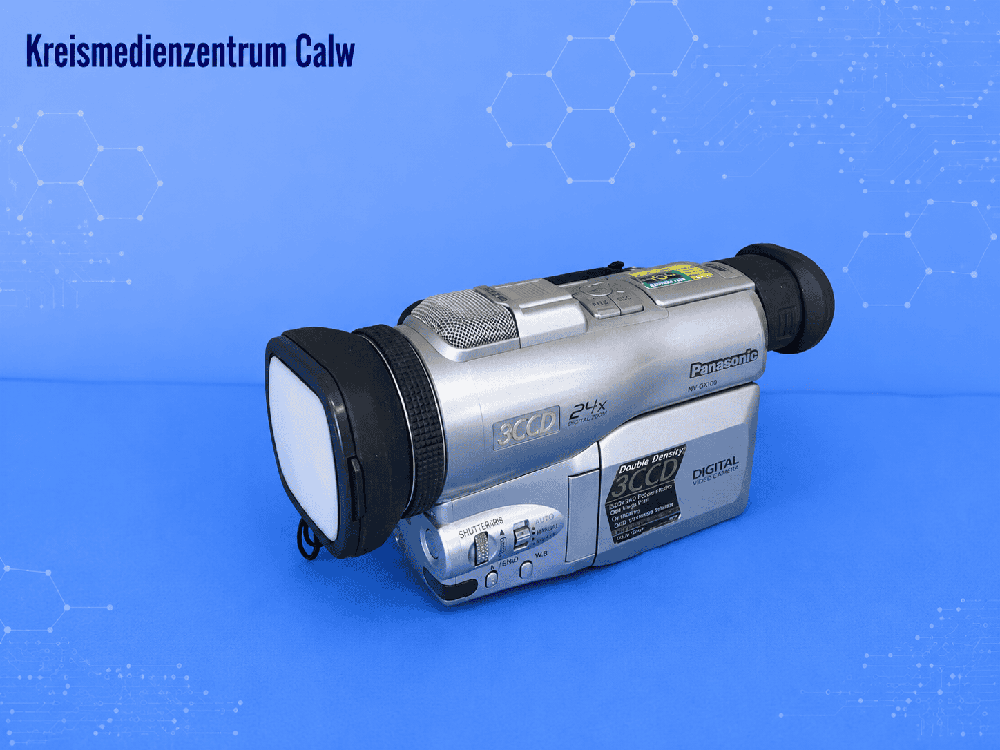 Panasonic Camcorder NV-DX-100 EG vor blauem Hintergrund mit Hexagon-Muster.