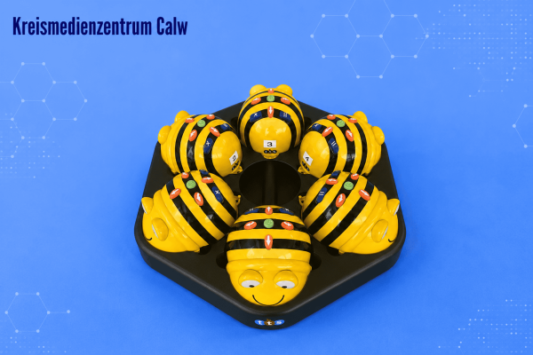 Sechs Bee-Bots Lernroboter auf Ladestation, ideal für Bildung.